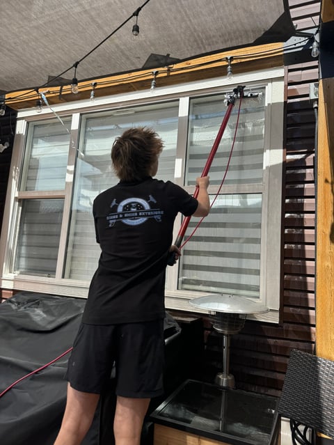 Person in black shirt installing or adjusting large horizontal sliding window with striped glass panes